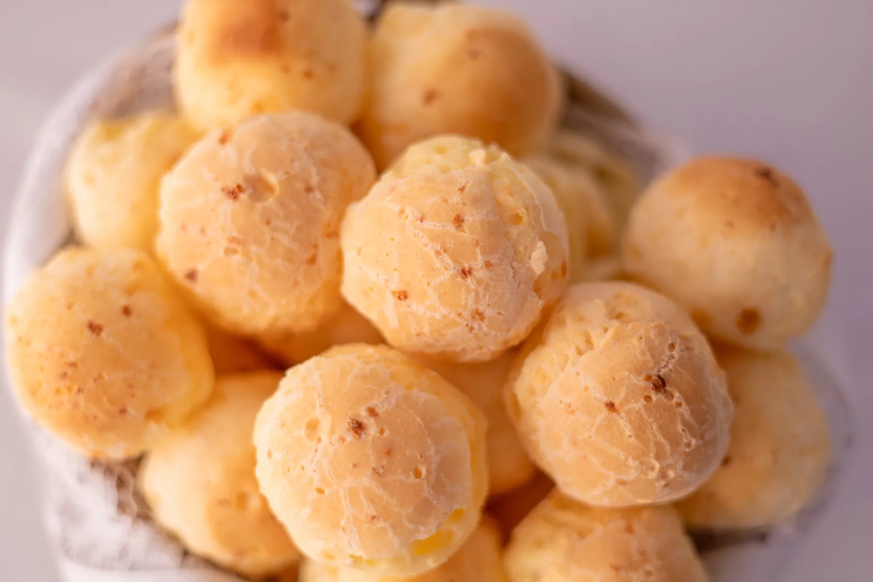 Pão de queijo Kent dourado, recém-saído da fornada, na cesta